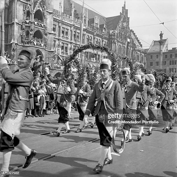 Some men in typical costumes crossing Marienplatz during the Oktoberfest. Munich, 1951