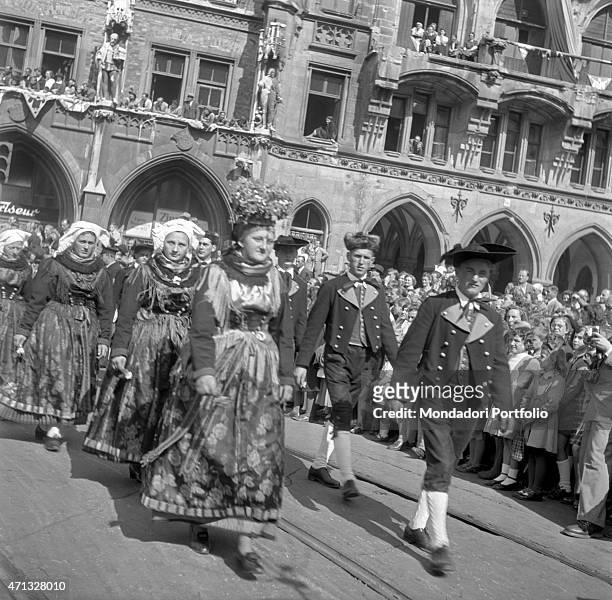 Men and women in typical costumes crossing Marienplatz during the Oktoberfest. Munich, 1951