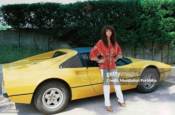 Close up of the British singer Kate Bush, pose for a photo shoot with a jellow Ferrari car. Italy 1978