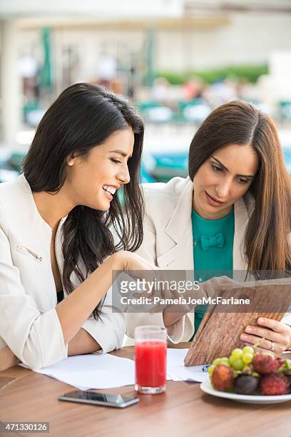 business lunch, zwei middle eastern geschäftsfrauen sie einen tablet pc - dubai spa stock-fotos und bilder