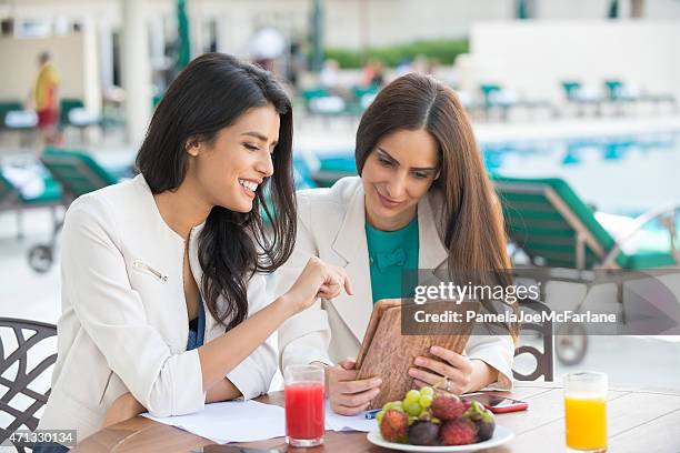 middle eastern geschäftsfrauen reviewingtablet pc am café im freien - dubai spa stock-fotos und bilder