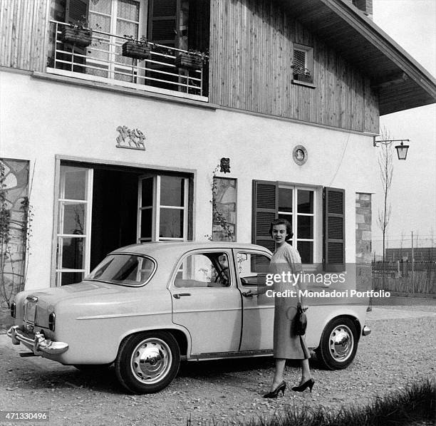 Italian actress Anna Maria Ferrero opening the door of an Alfa Romeo Giulietta. Milan, April 1955