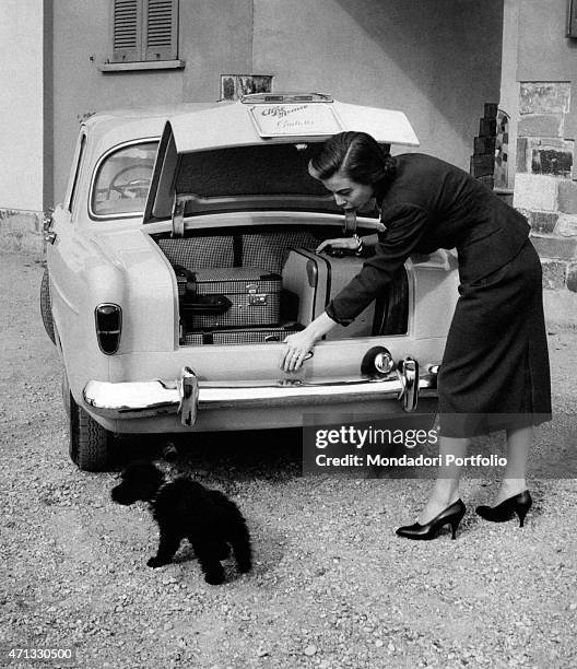 Italian actress Anna Maria Ferrero putting her luggage into an Alfa Romeo Giulietta. Milan, April 1955