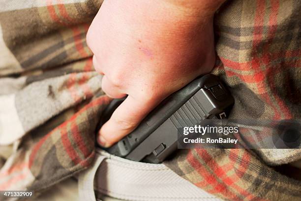 concealed firearm drawn from waistband - hiding stock pictures, royalty-free photos & images