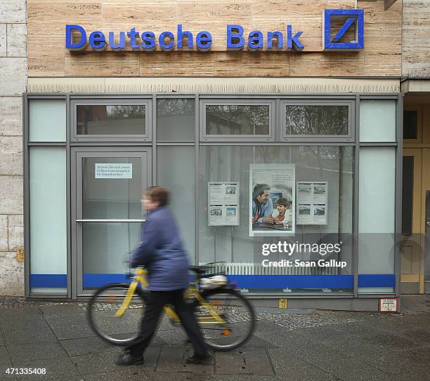 Woman pushes a bicycle past a branch of German bank Deutsche Bank on April 27, 2015 in Berlin, Germany. Deutsche Bank announced earlier in the day...