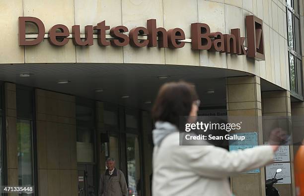 Woman drops refuse into a trash can next to a branch of German bank Deutsche Bank on April 27, 2015 in Berlin, Germany. Deutsche Bank announced...