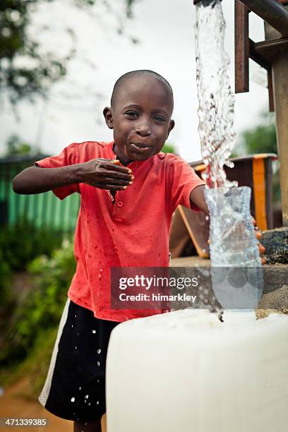 african boy by water pump - african africa child drinking water cup stock pictures, royalty-free photos & images