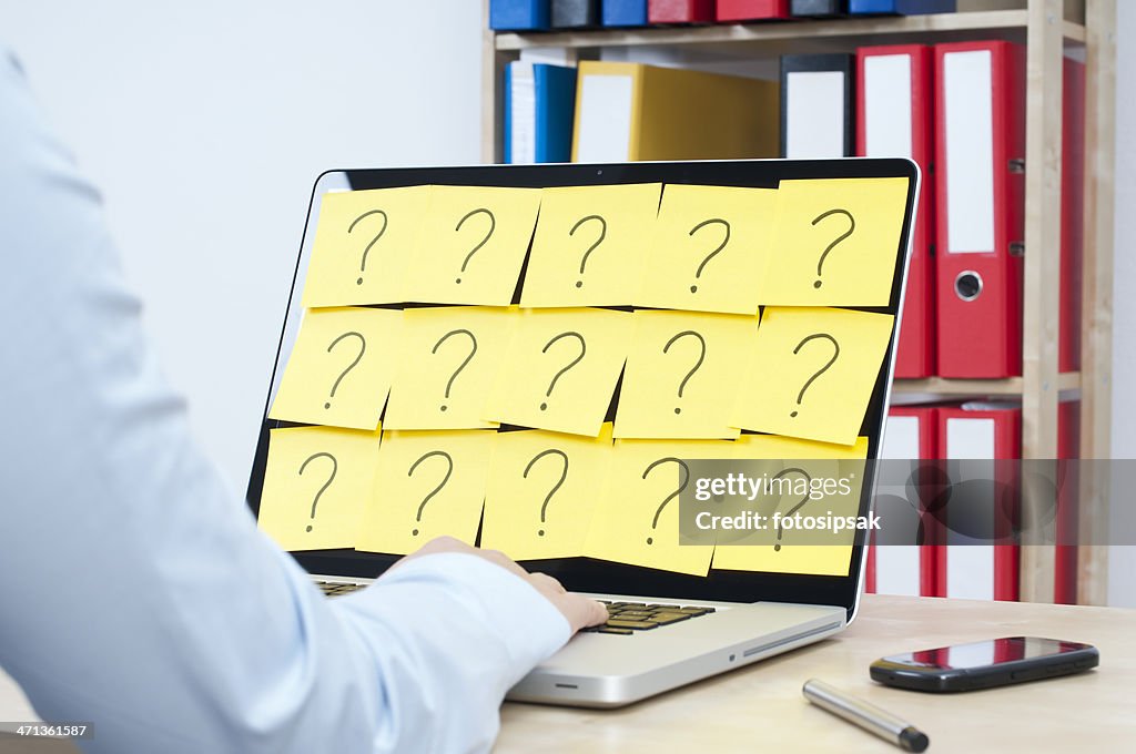 Person on their laptop covered in question marks