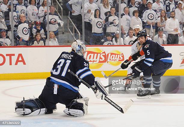 Ryan Getzlaf of the Anaheim Ducks and Mark Stuart of the Winnipeg Jets watch as goaltender Ondrej Pavelec deflects the puck away from the net during...