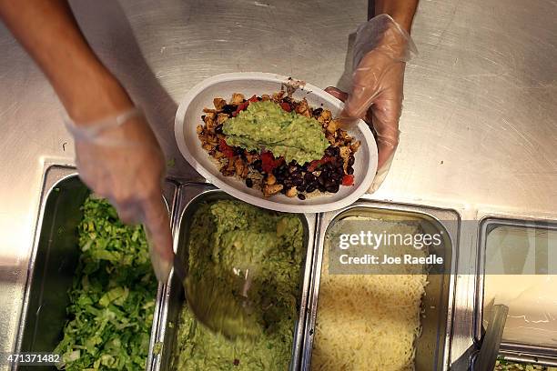 Chipotle restaurant workers fill orders for customers on the day that the company announced it will only use non-GMO ingredients in its food on April...