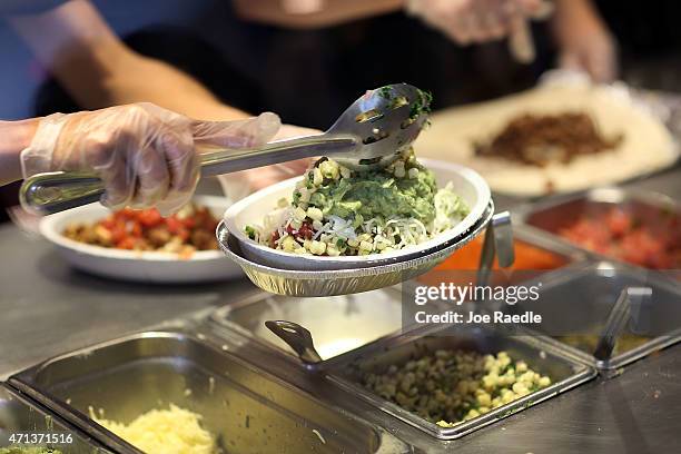 Chipotle restaurant workers fill orders for customers on the day that the company announced it will only use non-GMO ingredients in its food on April...