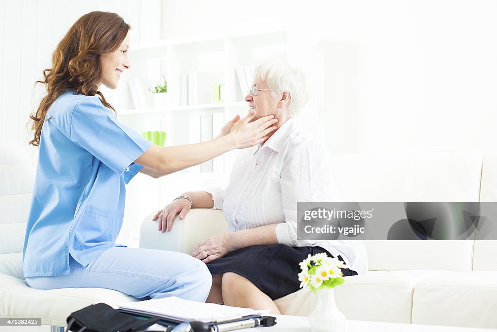 Médico dando glândulas exame com mulher idosa.