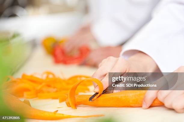 closeup of a restaurant cook cutting carrots into slices - peeler stock pictures, royalty-free photos & images