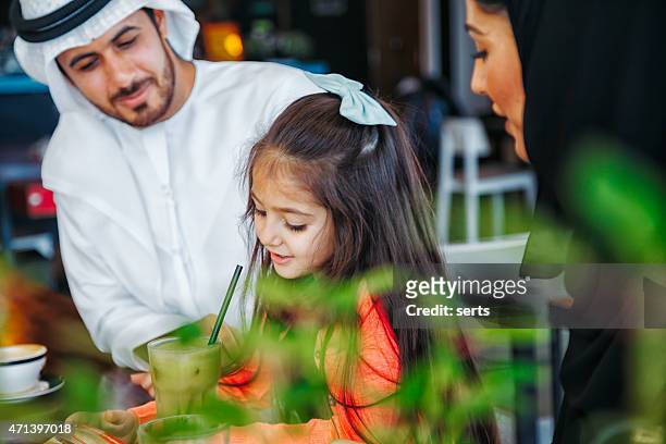 traditional young arab family enjoying at cafe - dubai park stock pictures, royalty-free photos & images