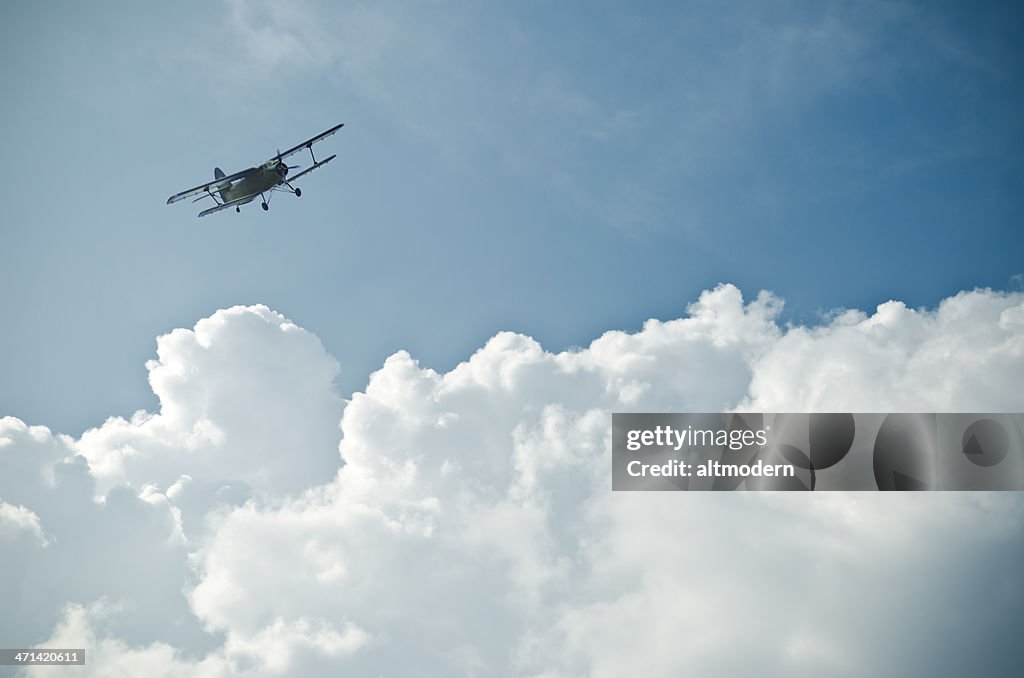 Small plane flying above the clouds in the blue sky