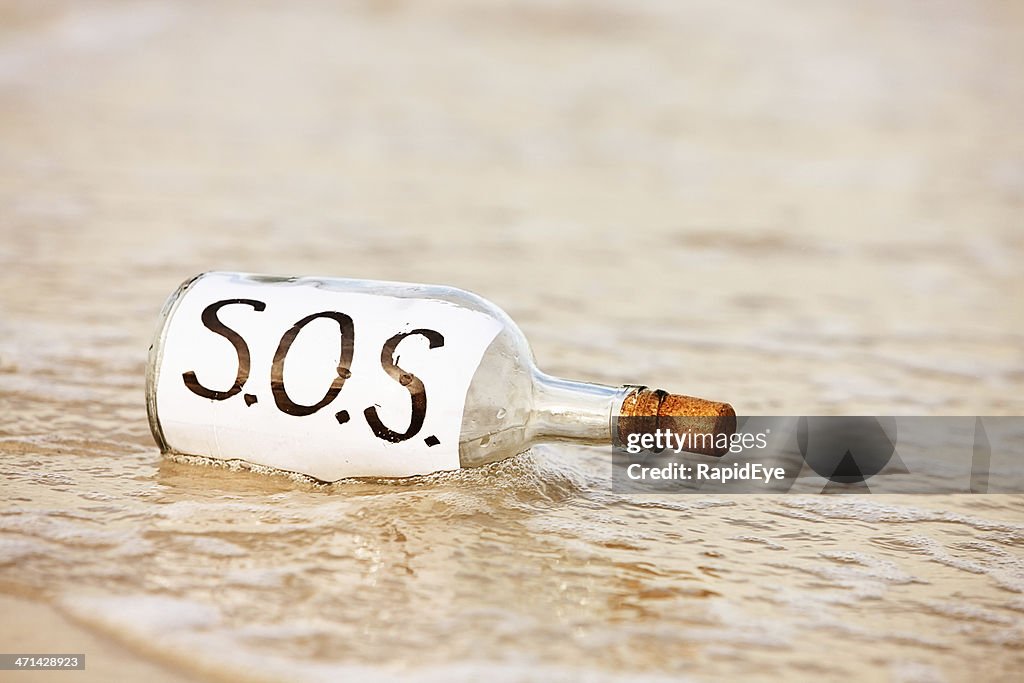 SOS message in bottle being washed away by tide