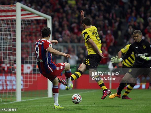 Robert Lewandowski of Bayern Muenchen scores his first goal against goalkeeper Mitchell Langerak and Sokratis of Dortmund during the DFB Cup semi...