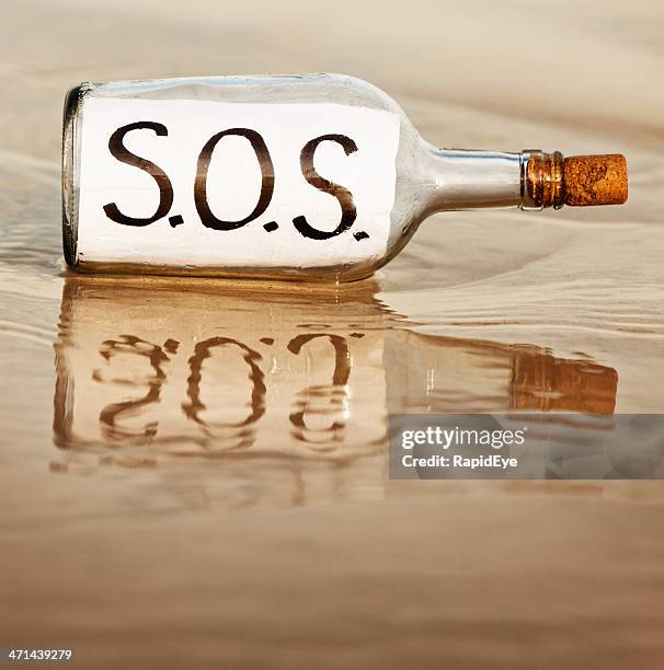 sos says desperate message in bottle at waters edge - message in a bottle stock pictures, royalty-free photos & images