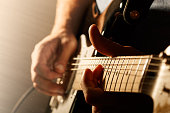 Close up of mans fingers playing electric guitar