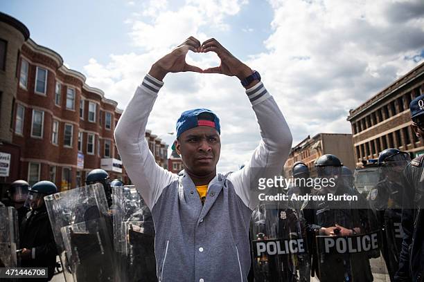 Man makes a heart shape with his hands during a protest near the CVS pharmacy that was set on fire yesterday during rioting after the funeral of...