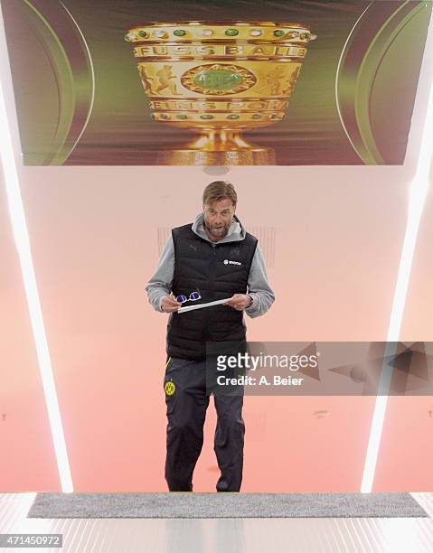 Team coach Juergen Klopp of Dortmund walks under a huge poster showing the DFB Cup trophy in the players' tunnel before the DFB Cup semi final match...