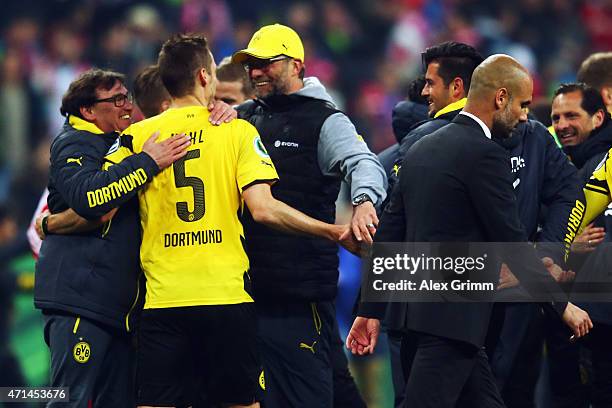 Head coach Pep Guardiola of Muenchen walks by as Juergen Klopp of Dortmund celebrates with Sebastian Kehl after the DFB Cup Semi Final match between...