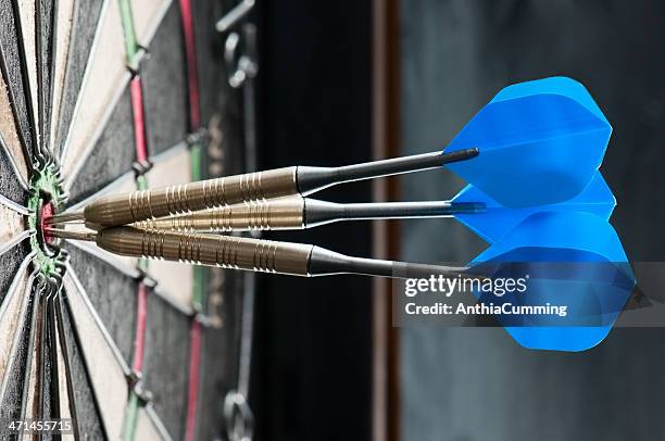 dart board with three darts in the bulls eye - darts stockfoto's en -beelden