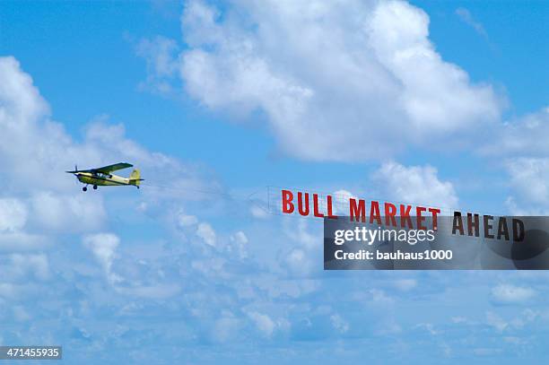 airplane is towing a banner against the blue sky with clouds - propellervliegtuig stockfoto's en -beelden