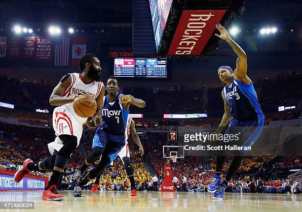 James Harden of the Houston Rockets looks to pass the basketball in front of Al-Farouq Aminu and Charlie Villanueva of the Dallas Mavericks of the...