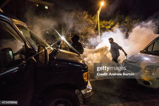 Protester runs through tear gas as police enforce a mandatory, city-wide curfew of 10PM near the CVS pharmacy that was set on fire yesterday during...