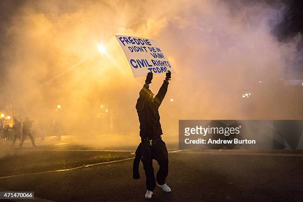 Protester walks through tear gas as police enforce a mandatory, city-wide curfew of 10PM near the CVS pharmacy that was set on fire yesterday during...