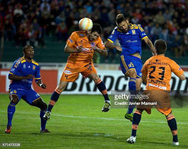Ignacio Gonzalez of Universitario Sucre and Rafael Sobis of Tigres jump to head the ball during a first leg match between Universitario Sucre and...