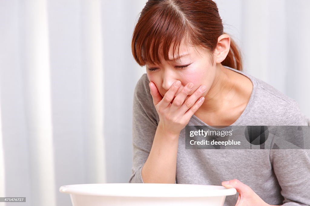 Young woman looking nauseous with hand over mouth