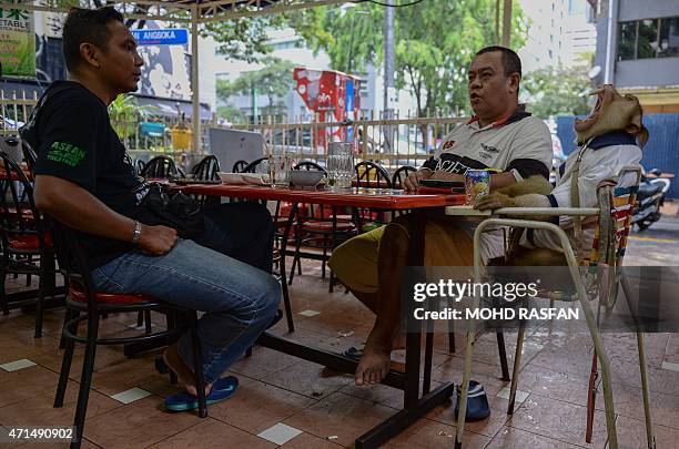 This photo taken on April 25, 2015 shows Jamil Ismail talking to a friend as his male monkey named "JK" yaws during their lunch at a restaurant in...