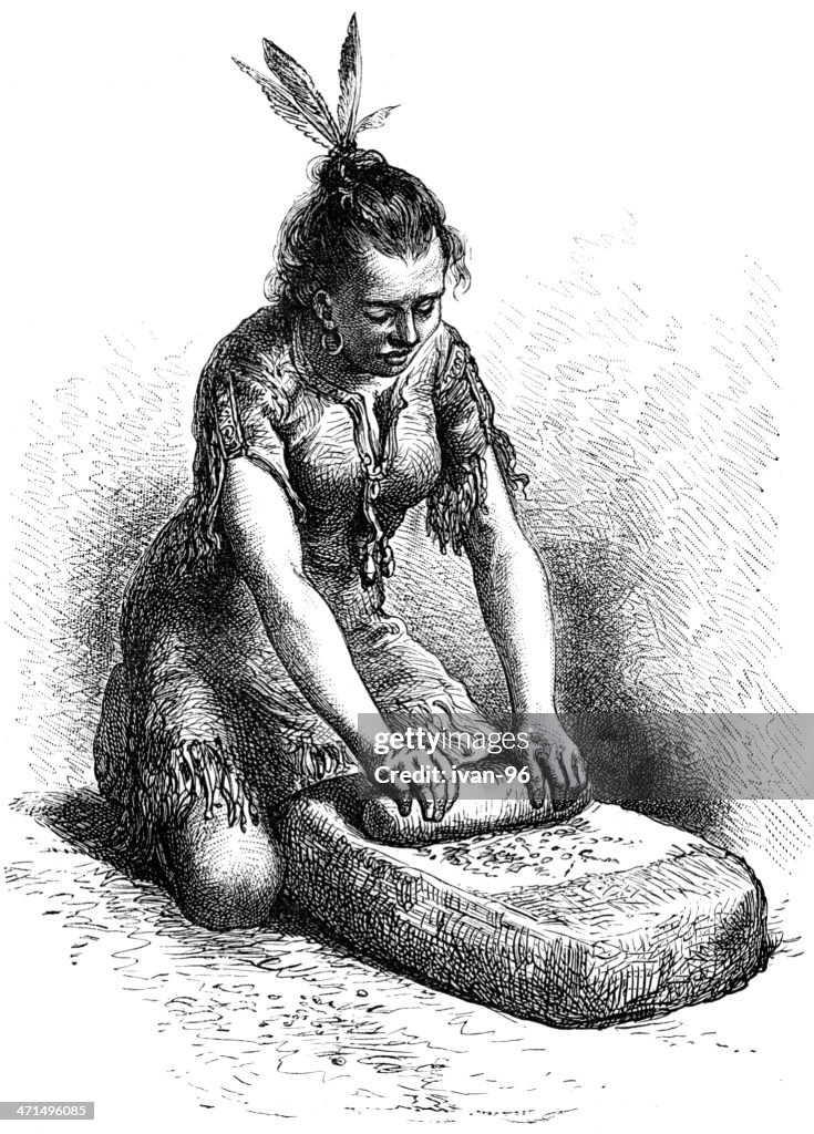 Indian woman grinds corn on stone