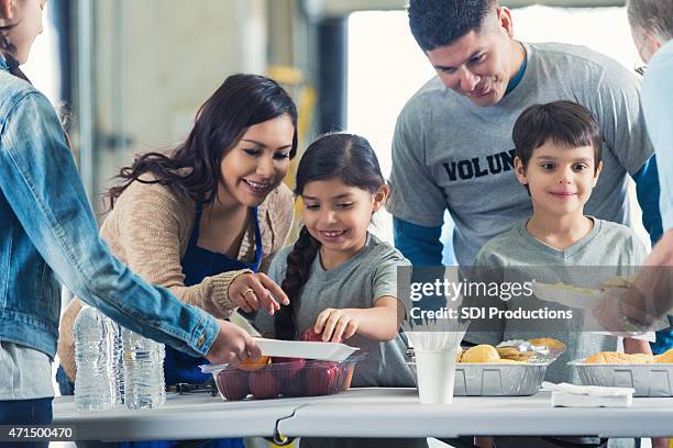 family serving meals while they volunteer in soup kitchen together - boy gift stockfoto's en -beelden