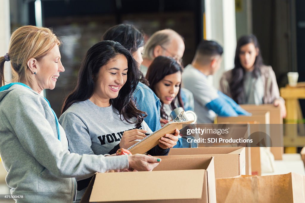 Diverse adults packing donation boxes in charity food bank