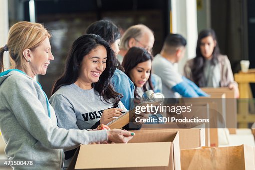 Diverse adults packing donation boxes in charity food bank Diverse adults packing donation boxes in charity food bank