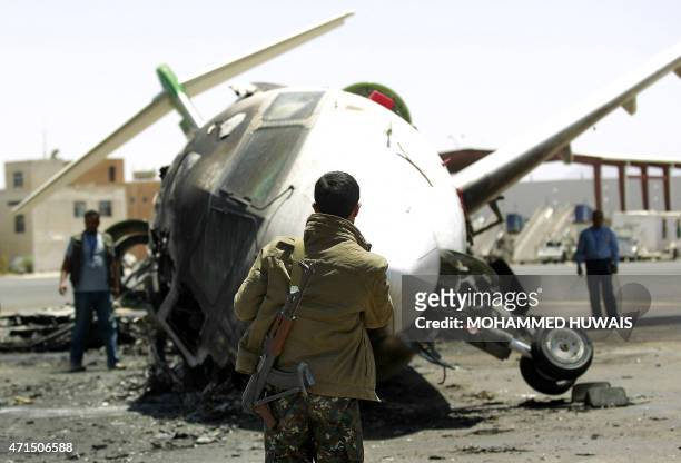 Yemeni security and airport officials stand next to a destroyed Felix Airways plane, after it was hit in an air strike, at the international airport...
