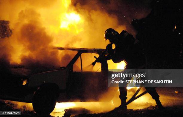 Firemen tries to put out a burning car, 05 November 2005 in the Cite de l'Europe neighborhood in Aulnay-sous-Bois, a northern surburb of Paris, on...