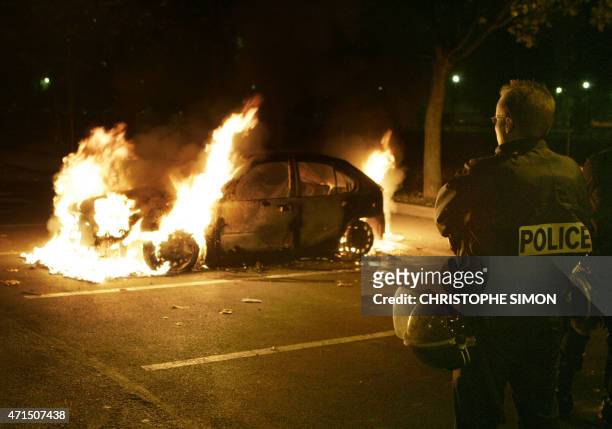 Policeman views a burning car in Aulnay-sous-Bois north of Paris suburbs, 05 November 2005. Arson attacks flared around Paris and in other parts of...