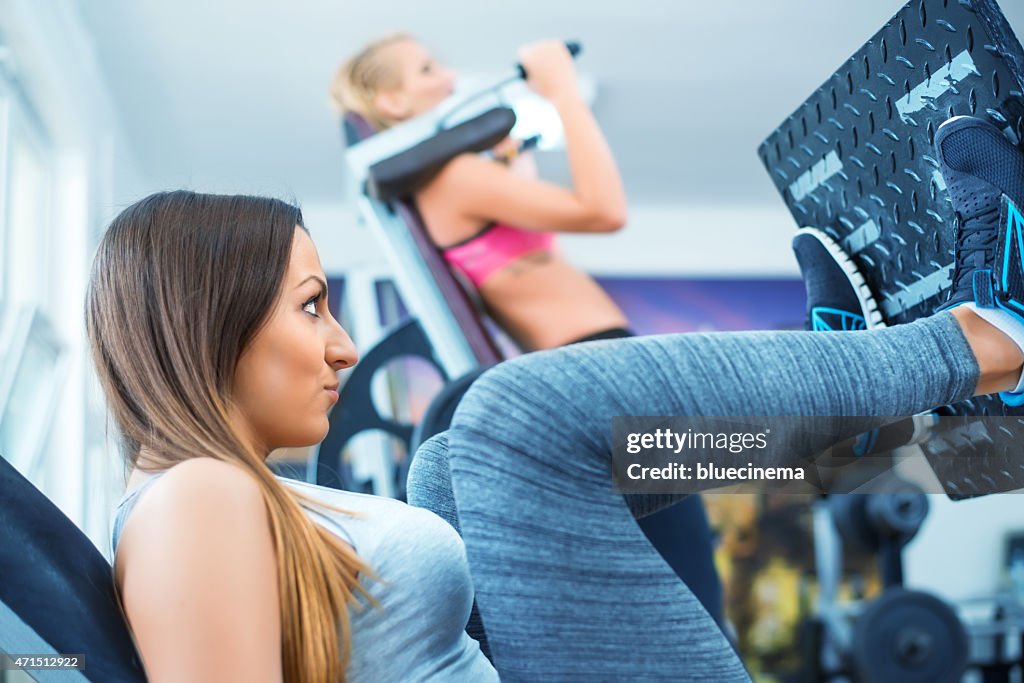 Women exercising on leg press in gym