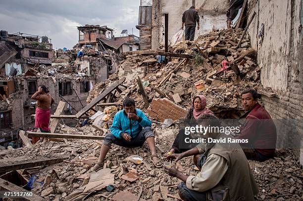 Nepalese earthquake victims take a break as they search for their belongings among debris of their home on April 29, 2015 in Bhaktapur, Nepal. A...