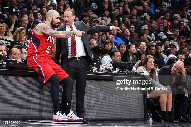 Pero Antic and Mike Budenholzer of the Atlanta Hawks talk during Game Three of the Eastern Conference Quarterfinals against the Brooklyn Nets during...