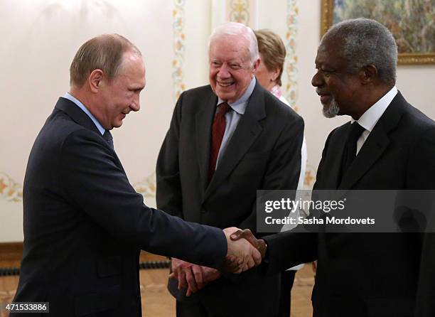 Russian President Vladimir Putin shakes hands with former UN Secretary-General Kofi Annan as former U.S.President Jimmy Carter looks on during a...