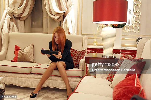 "The Italian Minister of Tourism Michela Vittoria Brambilla seats on a red sofa with a tablet in her hands in the suite of the Savoia Hotel, where...