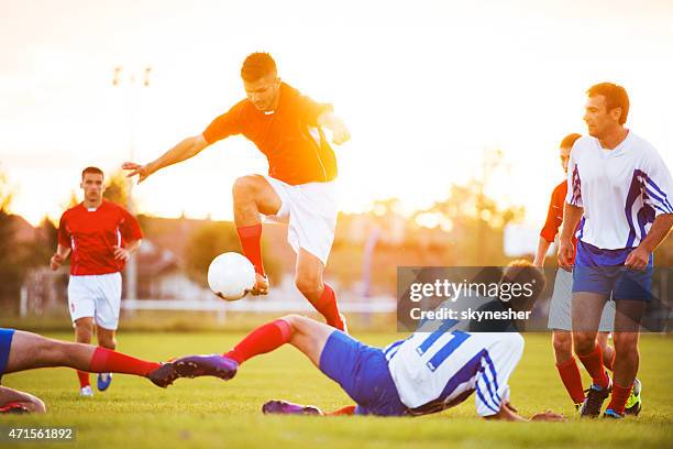 fußball-spieler fußball spielen bei sonnenuntergang. - sportlicher zweikampf stock-fotos und bilder