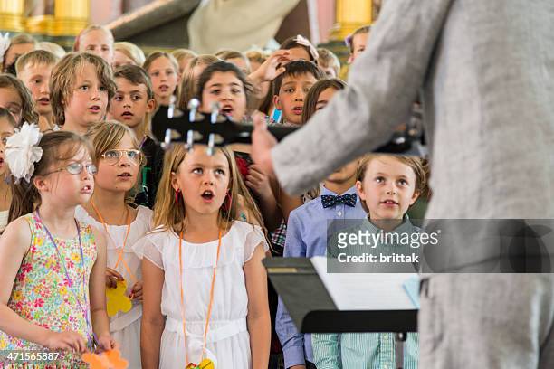 scuola bambini cantando alla chiesa. - coro foto e immagini stock