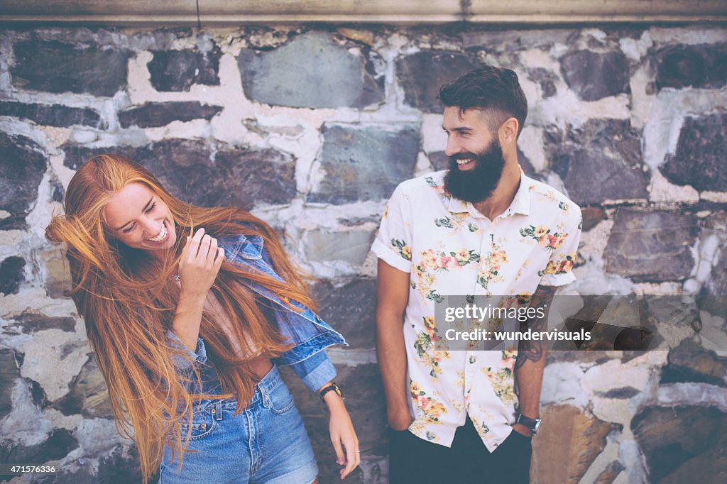 Hipster bonito casal rindo na frente de uma parede de pedras