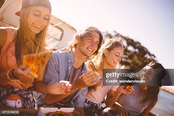 teenaged friends sitting together outside eating pizza - standing water stock pictures, royalty-free photos & images